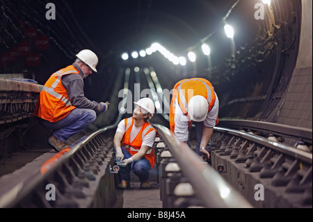 Contractors installing prism targets in underground station to detect structural movement caused by nearby construction works. Stock Photo