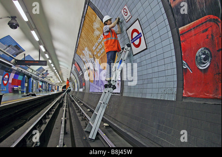 Contractors installing prism targets in underground station to detect structural movement caused by nearby construction works. Stock Photo