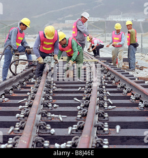 Contractors laying temporary wooden-sleepered tracks into rail depot during construction of the new Hong Kong Airport. Stock Photo