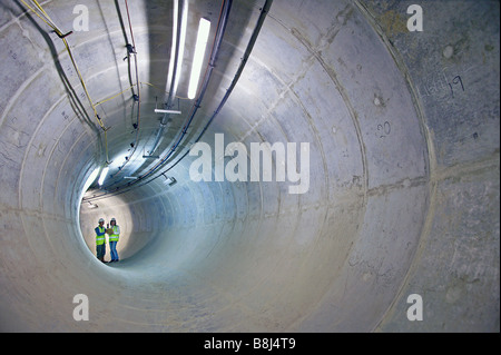 Engineers inspect access adit to main power cable tunnel in London, lined with concrete supporting segments. Stock Photo