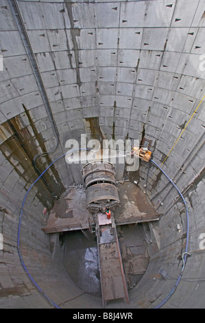 Engineer inspecting tunnel boring machine which has completed excavation of power cable tunnel, arriving in deep access shaft. Stock Photo