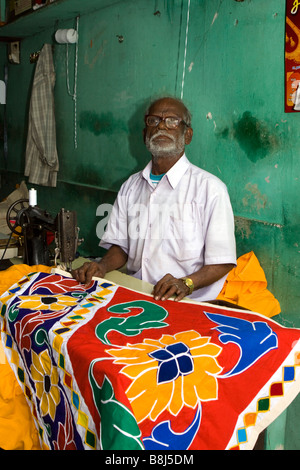 India Tamil Nadu Kumbakonam TSR Big Street tailor in small roadside worksop making colourful tomboi textile temple hanging Stock Photo