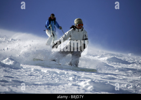 Skier and a snowboarder going downhill on Mount Hood in Oregon in the United States Stock Photo