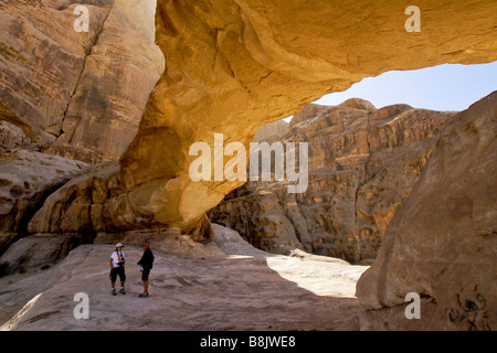 Hikers under natural arch at Wadi Rum, Jordan Stock Photo