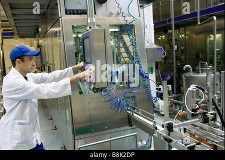 The line for bottling milk. Worker with the administrator terminal. Stock Photo