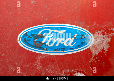 Dusty rusted and peeling off Ford logotype on red painted car. Stock Photo