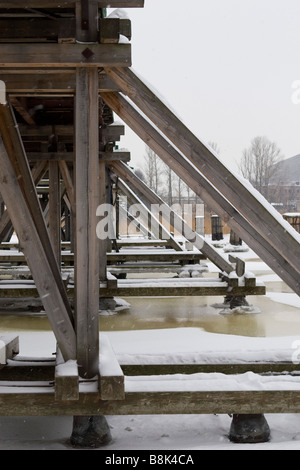 Frozen river bridge wooden piers construction view. Stock Photo