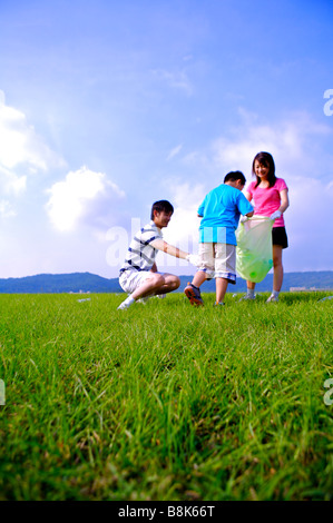 Family with one child putting the empty bottles into the garbage bag Stock Photo