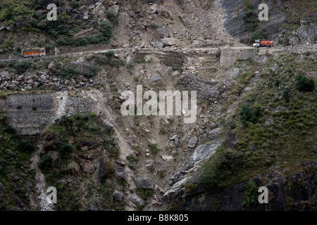 Two trucks are meeting on a dramatic road in the Indian Himalaya which has been temporarily repaired after a land slide. Stock Photo