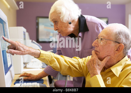 Senior woman helping senior man use computer Stock Photo