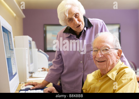 Senior woman helping senior man use computer Stock Photo
