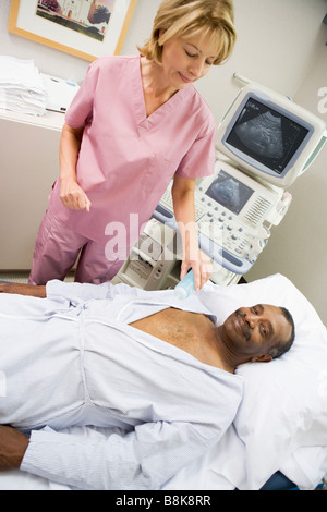 Nurse Checking On Patient Lying On Hospital Bed Stock Photo