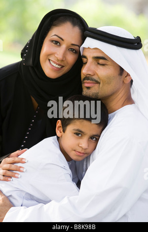 Family outdoors in park embracing and smiling (selective focus) Stock Photo