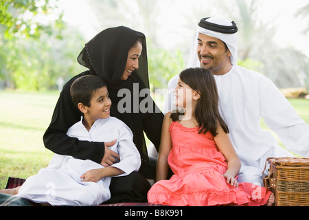 Family outdoors in park having a picnic and smiling (selective focus) Stock Photo