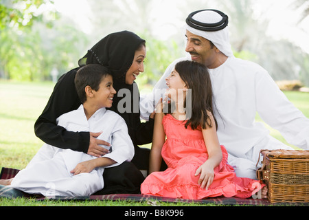 Family outdoors in park having a picnic and smiling (selective focus) Stock Photo