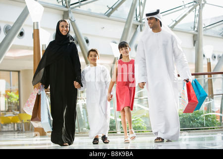 Family walking in mall holding hands and smiling (selective focus) Stock Photo