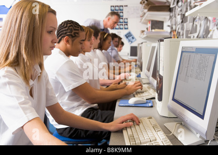Students working on computer workstations with teacher Stock Photo