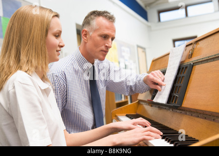 Female student learning piano with teacher in classroom Stock Photo