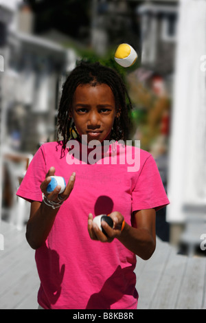 Eleven year-old Black American girl juggling three balls. Model Released Stock Photo