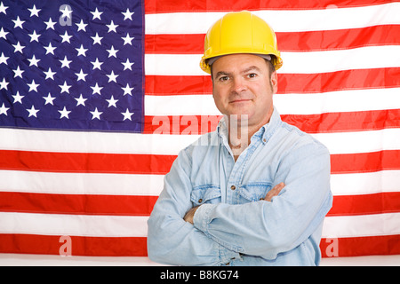 Patriotic construction worker standing in front of an American flag Photographed in front of flag not composite image Stock Photo