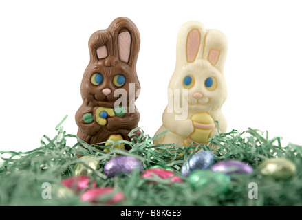 Milk chocolate and white chocolate Easter bunnies in love running through a field of easter grass and chocolate eggs Stock Photo