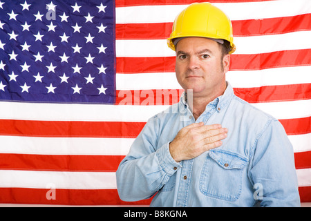 Patriotic american worker with his hand over his heart in front of the US flag Photographed in front of flag not composite image Stock Photo