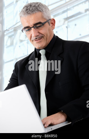 Creative looking mature businessman working on laptop computer Stock Photo