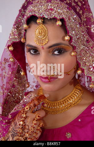 Pretty Asian or Indian Bride wearing a red dress and ornaments Stock Photo