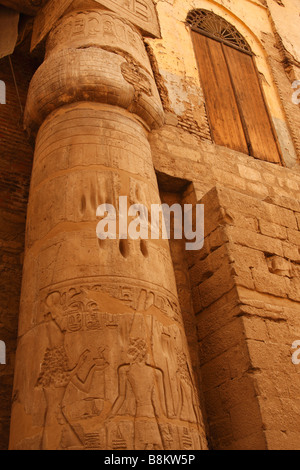 Large stone papyrus column with carved hieroglyphics next to old wooden door of Abu el-Haggag Mosque, Luxor temple ruins, Egypt Stock Photo