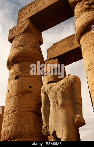 Headless statue of pharaoh beneath large stone carved papyrus columns, Great Court of Ramses II, Luxor Temple, Egypt Stock Photo