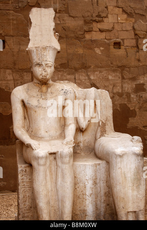 Damaged stone statue of pharaoh sitting on throne, Great Court of Ramses II, Luxor Temple, Egypt Stock Photo