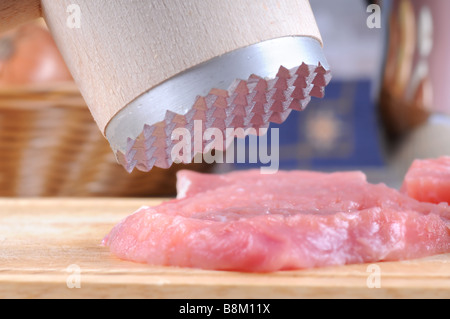 Tenderization of fresh pork steaks on wooden chopping board. Stock Photo