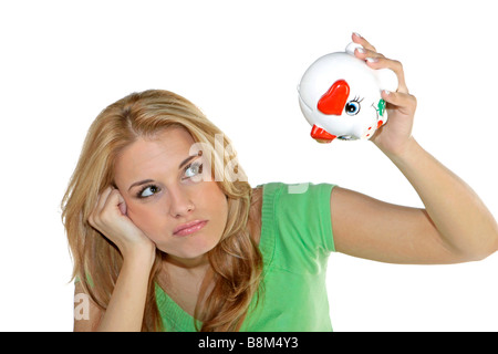 Unhappy young woman checking cash in empty piggy bank Stock Photo