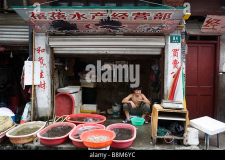 Young boy keeping a shellfish store ine the old chinese quarter of Shanghai, China Stock Photo
