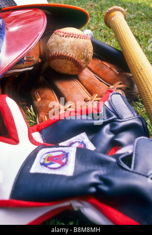 Collection of baseball gear on grass ball bat glove cap hat batting safety Stock Photo