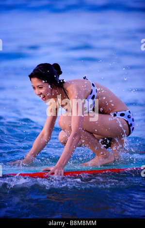 Woman floating on the sea with the surfboard and smiling happily Stock Photo