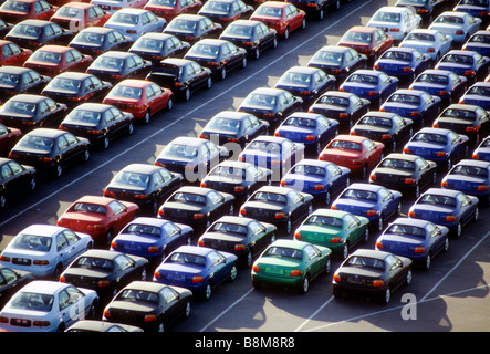 New cars sit in rows on dock after being unloaded from ship economy oil mileage market sell overload inventory auto vehicle Stock Photo