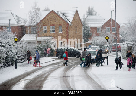 Parents walking their children to school across a snow and ice covered road on a winters day in England Stock Photo