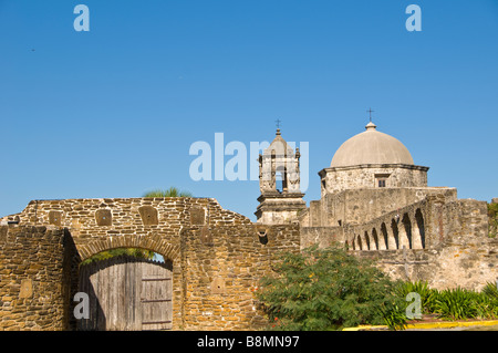 Mission San Jose exterior showing thick stone walls wood entrance door church bell tower and church dome  San Antonio Tx Stock Photo