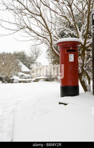 royal Mail red post box in the snow in the snow in a country village in Buckinghamshire England UK Stock Photo