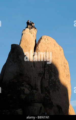 two rock climbers man and woman getting ready to descend from top of a rock pinnacle Hidden Valley Joshua Tree National Park Stock Photo