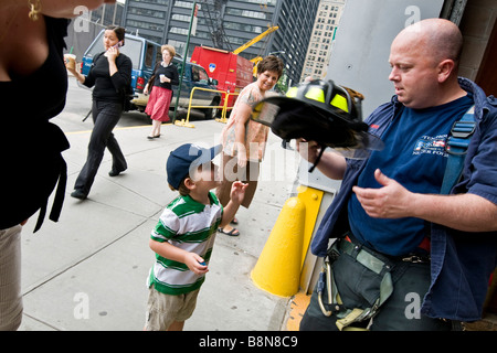 Young boy speaking to fireman outside New York city fire department. Stock Photo