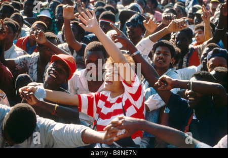 A happy and smiling crowd of people dance and wave their hands in the air at a pop concert in Johannesburg. Stock Photo