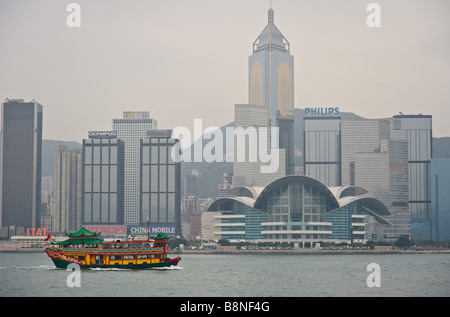 Colorful tour boat in Hong Kong's Victoria Harbour passing Central district and convention center Stock Photo