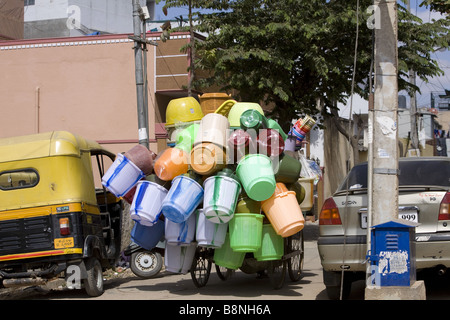 A street scene in Puttaparthi, India of a cyclist transporting lots of different coloured plastic buckets. Stock Photo