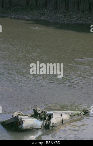 Dumped car in canal at low tide. Stock Photo