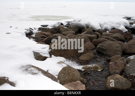Spring stream in stone boulders breaking throug thawing ice. Stock Photo