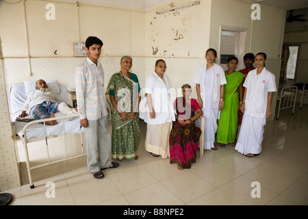 A bed ridden patient with family members and nursing staff in a general ward of the New Civil Hospital, Surat. Gujarat. India. Stock Photo
