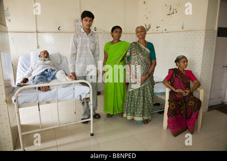 Family members with a bed ridden patient in a general ward of the New Civil Hospital, Surat. Gujarat. India. Stock Photo
