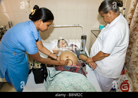 Maternity nurses examine heavily pregnant woman patient in the maternity ward of the New Civil Hospital, Surat. Gujarat. Stock Photo